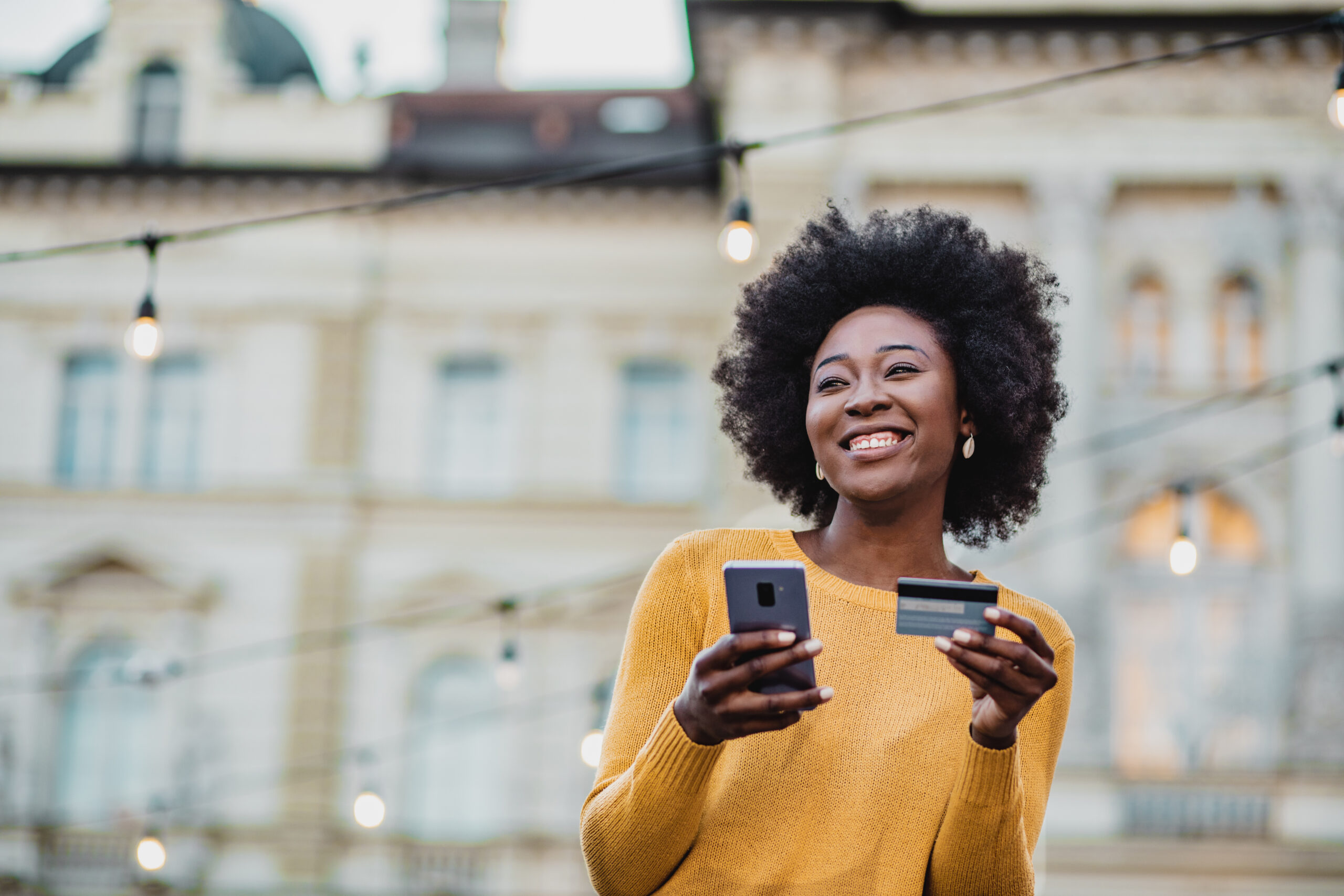 Happy woman walking holding a phone and credit card